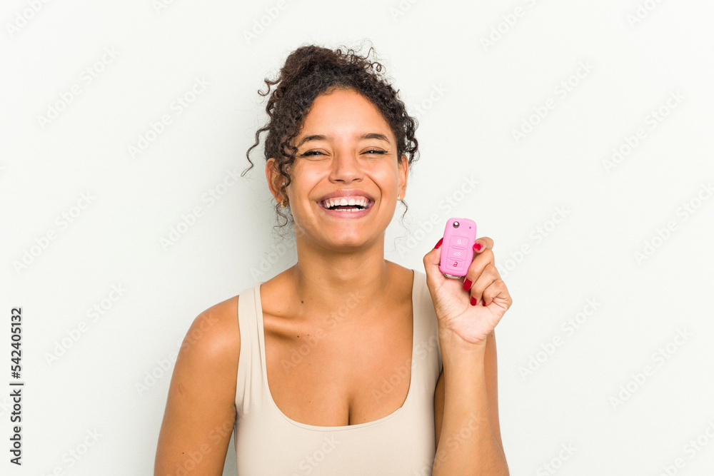 Young brazilian woman holding home keys isolated laughing and having fun. Young brazilian woman holding home keys isolated laughing and having fun.