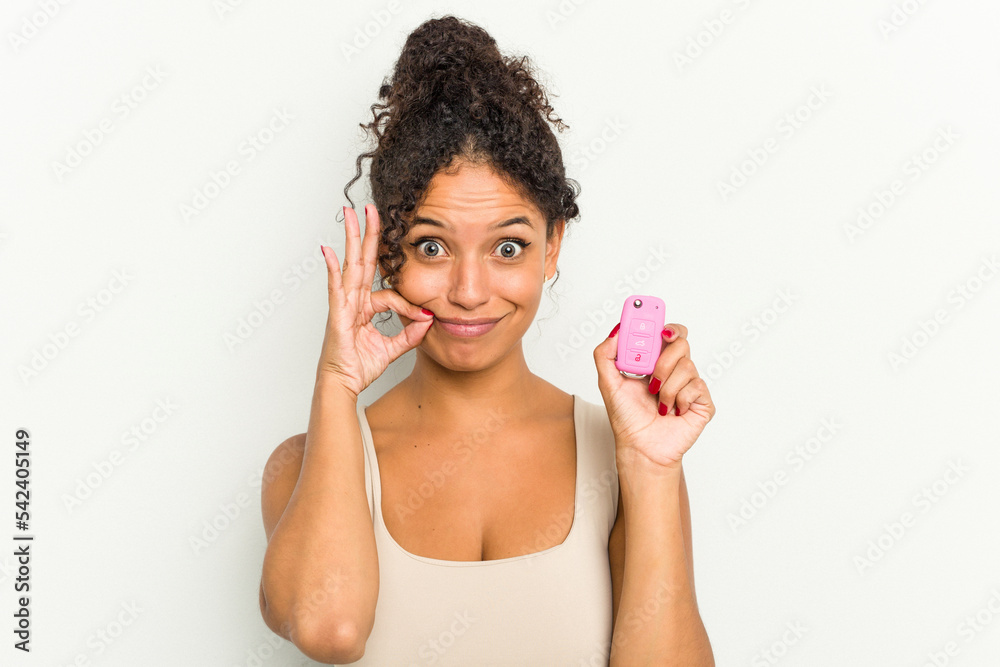 Young brazilian woman holding home keys isolated with fingers on lips keeping a secret. Young brazilian woman holding home keys isolated with fingers on lips keeping a secret.