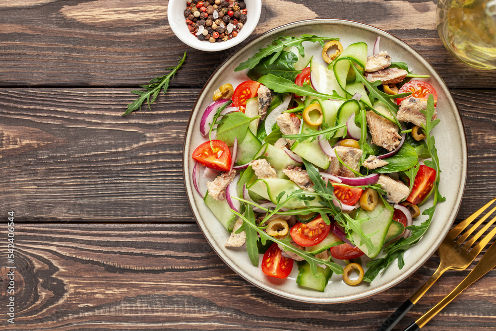 Fresh salad with vegetables and fish. Arugula, spinach, cucumbers, tomato, onions and fish in a plate on the table. Diet nutrition. Top view. Copy space Fresh salad with vegetables and fish. Arugula, spinach, cucumbers, tomato, onions and fish in a plate on the table. Diet nutrition. Top view. Copy space