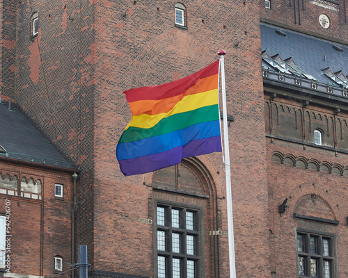 Photography Rainbow Flag waving on metal flag pole in front of Copenhagen City Hall building