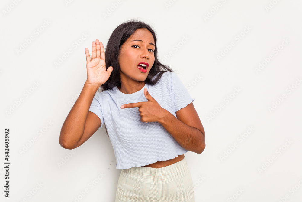 Young Indian woman isolated on white background trying to listening a gossip.