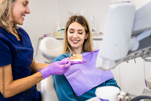 Female dentist takling with patient showing theet implant in dental clinic. photo