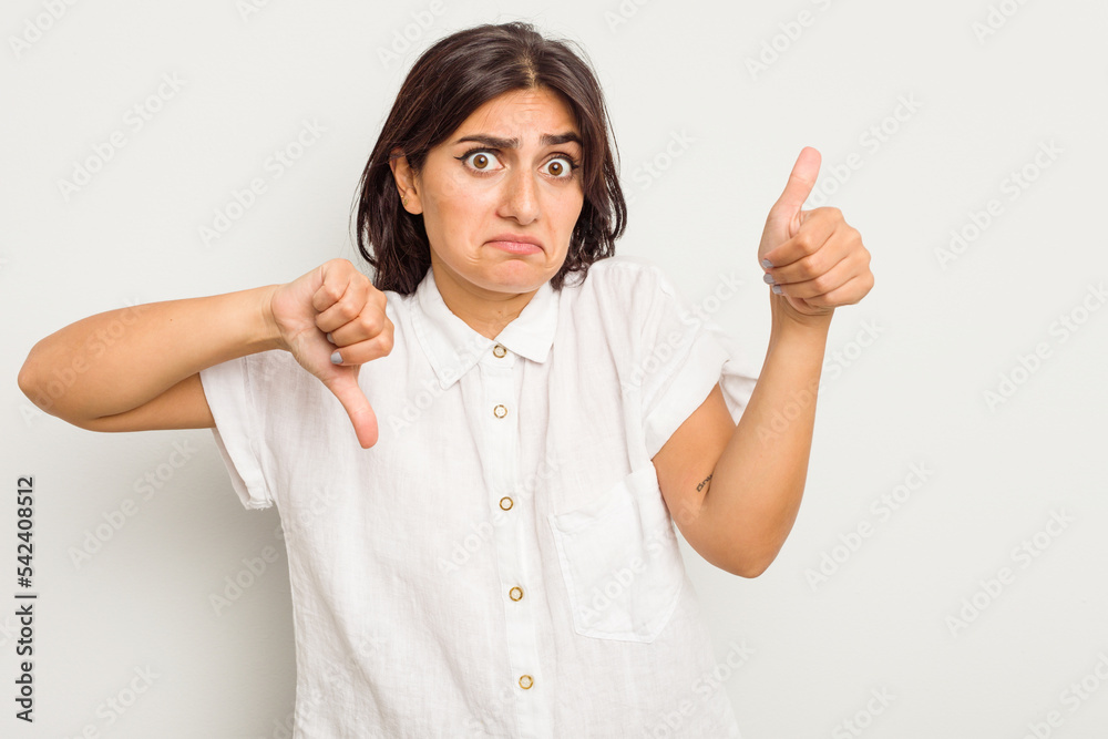 Young Indian woman isolated on white background showing thumbs up and thumbs down, difficult choose concept Young Indian woman isolated on white background showing thumbs up and thumbs down, difficult choose concept