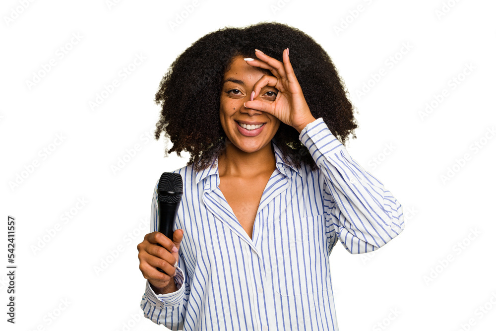 Young African American singer woman holding a microphone isolated excited keeping ok gesture on eye. Young African American singer woman holding a microphone isolated excited keeping ok gesture on eye.