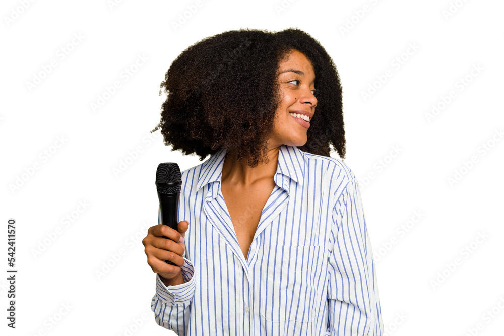 Young African American singer woman holding a microphone isolated looks aside smiling, cheerful and pleasant. Young African American singer woman holding a microphone isolated looks aside smiling, cheerful and pleasant.