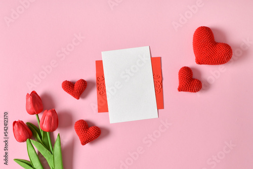 A mock-up of a kraft envelope with a blank sheet, tulips and knitted hearts.