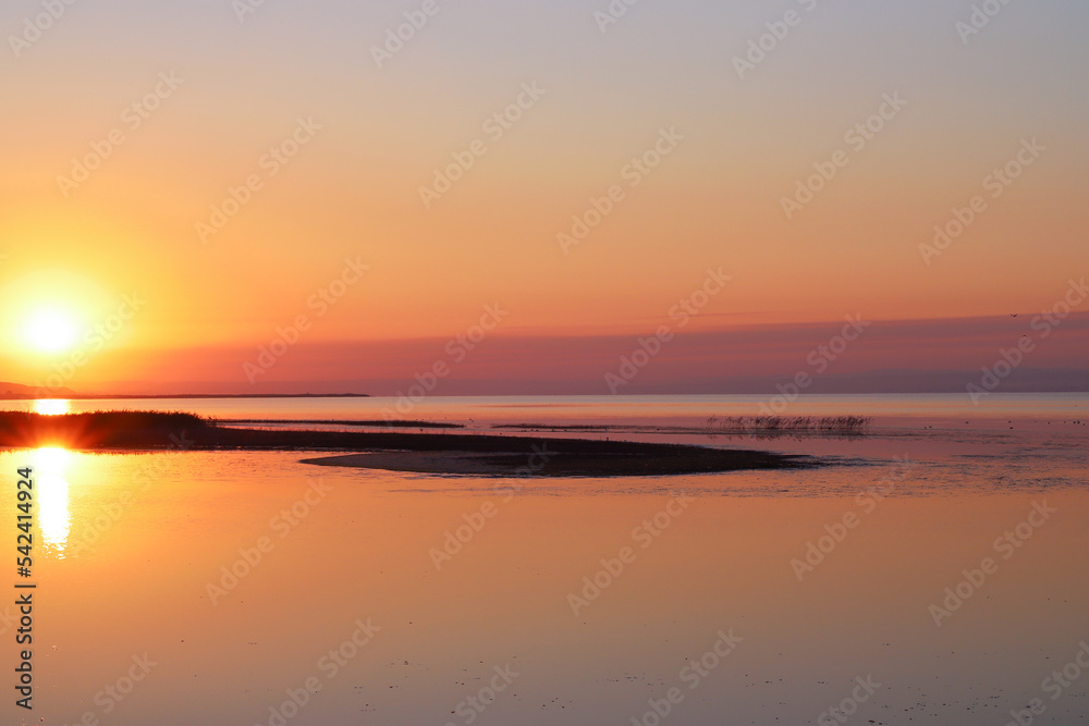 A big sun rises over the bay and hills on a summer morning. Beautiful sunrise landscape. Nature background