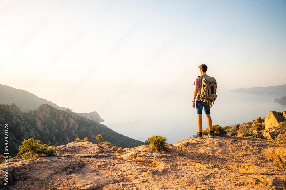 Solo traveler admiring the sunset on the sea on top of a mountain in Corsica. Success, new year 2023 . Calanques de Piana