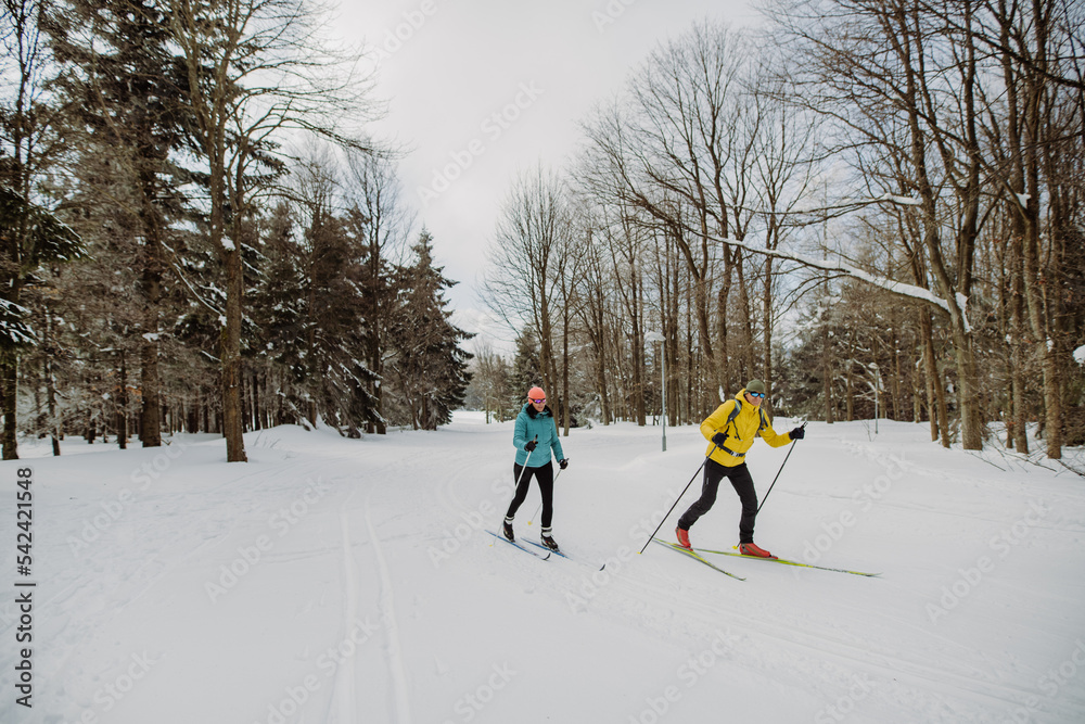 Senior couple skiing together in the middle of forest