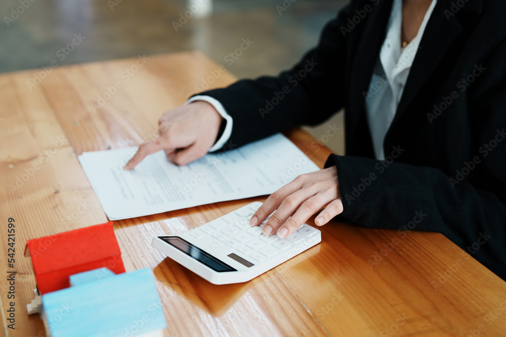 Guarantee, mortgage, contract, contract, signed, real estate agent or bank officer holding a calculator, submits a bid with a customer to buy a home before signing to make a deal Guarantee, mortgage, contract, contract, signed, real estate agent or bank officer holding a calculator, submits a bid with a customer to buy a home before signing to make a deal