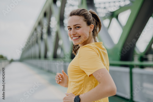 Fototapeta Naklejka Na Ścianę i Meble -  Young woman jogging at city bridge, healthy lifestyle and sport concept.