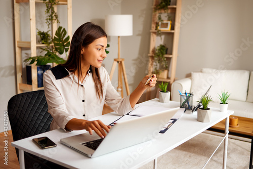 Portrait of young woman paying bills with credit card and laptop in office