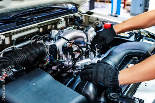 Auto mechanic working with open car hood in garage. Car repair service.