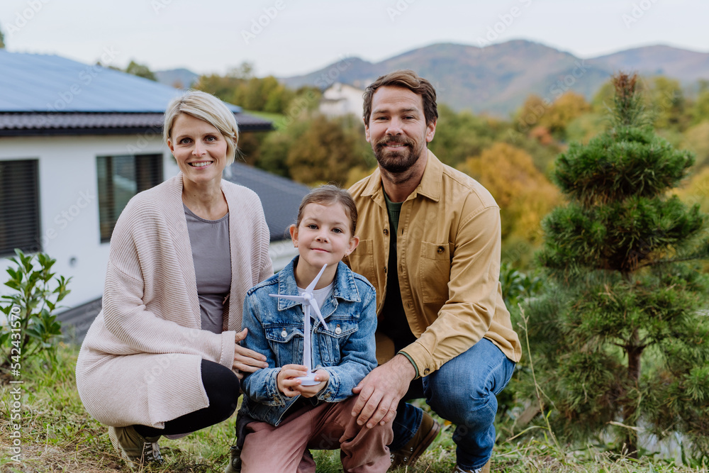 Happy family holding plastic model of wind turbine. Alternative energy, saving resources and sustainable lifestyle concept. Happy family holding plastic model of wind turbine. Alternative energy, saving resources and sustainable lifestyle concept.