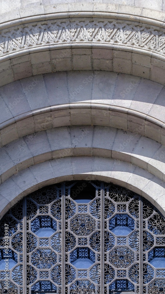 Vertical shot of an arch with beautiful carvings and an ornamental window rail. Yerevan, Armenia.