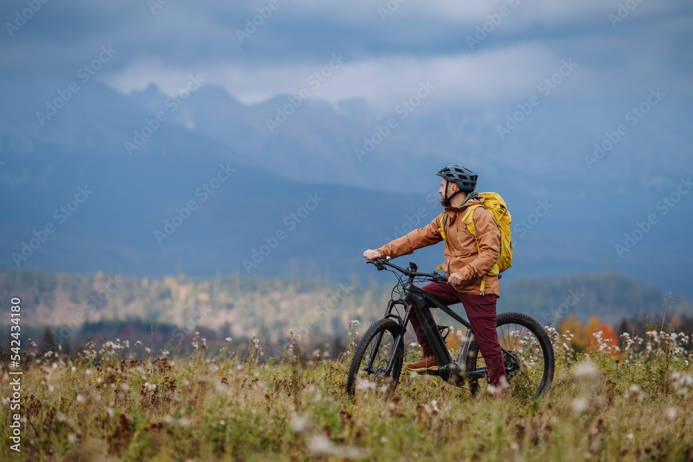 Fototapeta premium Active man on bike in the middle of autumn nature, admire mountains. Healthy lifestlye concept.