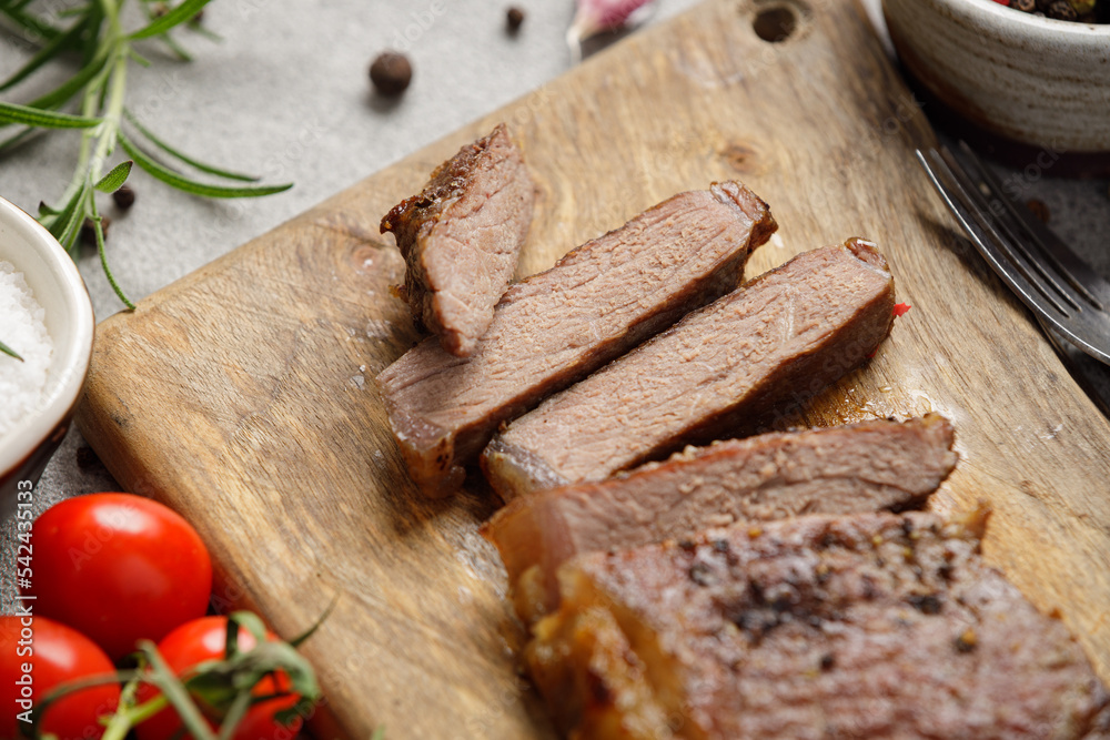 Grilled sliced beef steak well done on wooden cutting board. Top view.