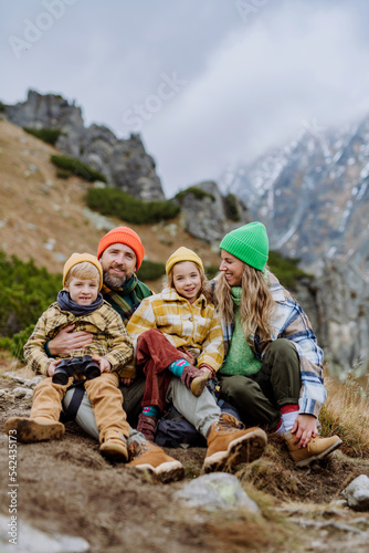 Happy family sitting and resting, during hiking together in autumn mountains.