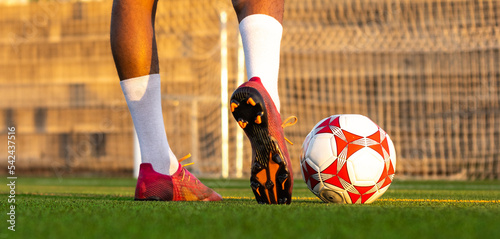Football player feet running with the ball in front of the field. Player feet with the ball scoring a goal. Football player on the field running with the ball