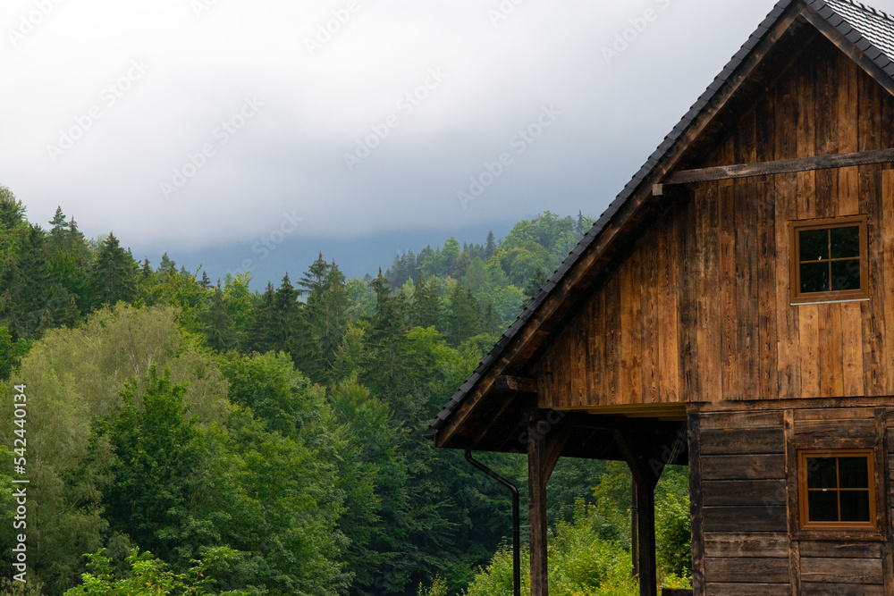 A wooden cottage in the mountains. Cloud forest in the background. Rainy day