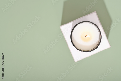 top view of burning candle on green background. copy space. natural coconut wax candle, organic ingredient