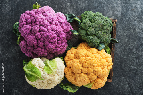 Colorful cauliflower. Various sort of cauliflower on old dark gray concrete background. Purple, yellow, white and green color cabbages. Broccoli and Romanesco. Agricultural harvest. Mock up.