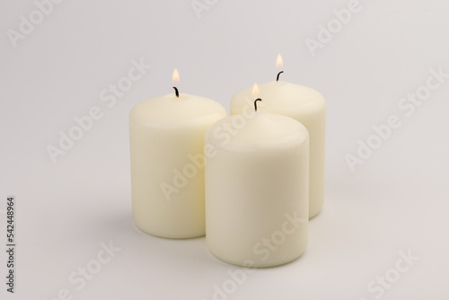 Burning white wax candles on white background.