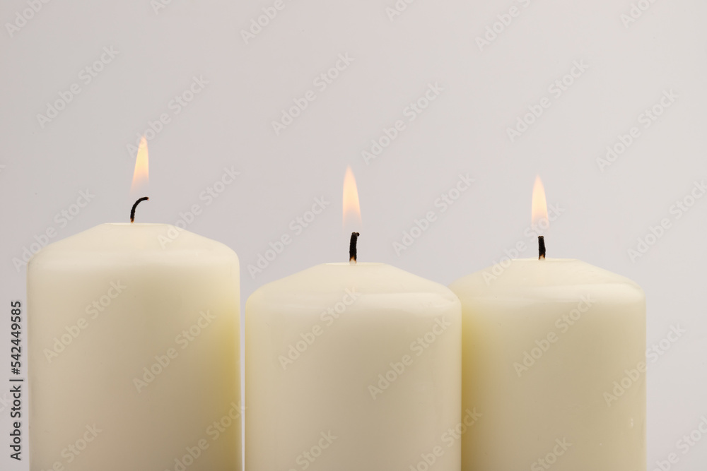 Burning white wax candles on white background. Burning white wax candles on white background.