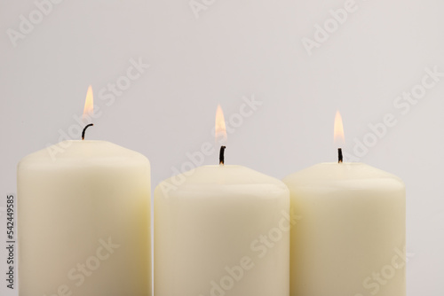 Burning white wax candles on white background.