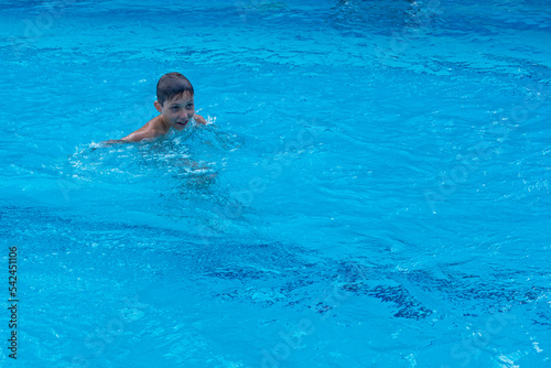 happy boy swims in the pool. family holiday