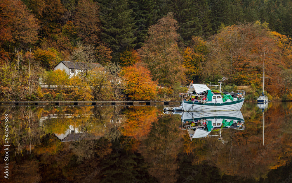 Peaceful scene of boat and reflection in Loch Oich with autumn vegetation Peaceful scene of boat and reflection in Loch Oich with autumn vegetation
