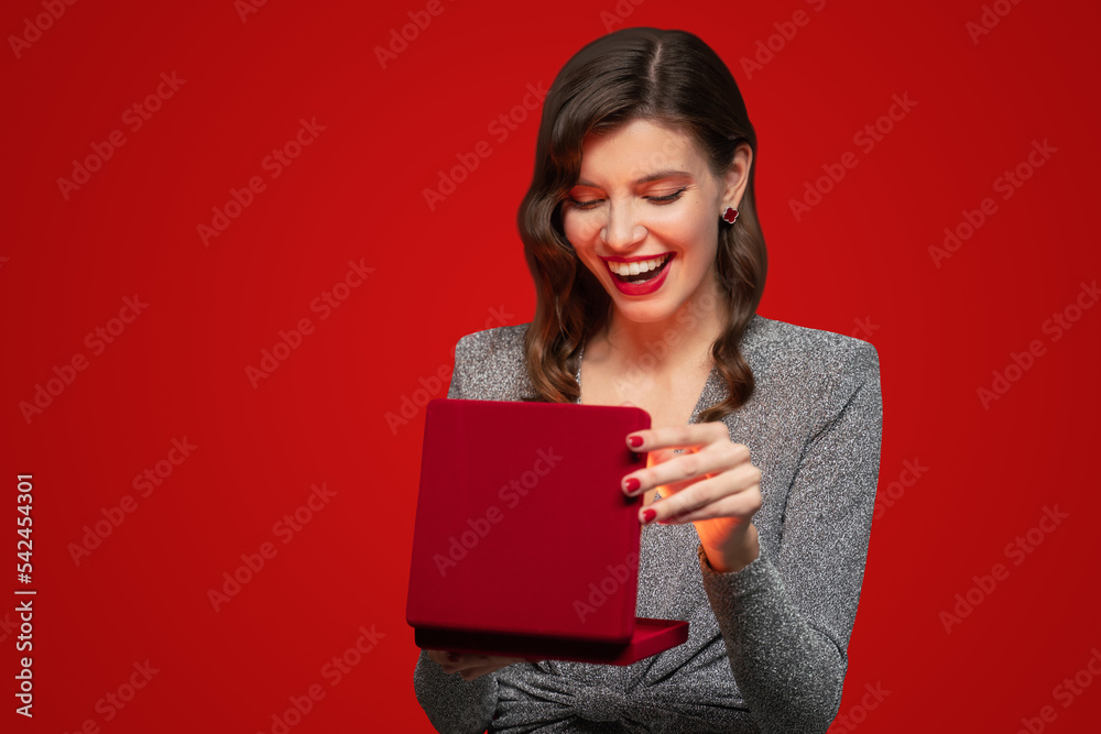 Woman opening present or christmas gift box on red background Woman opening present or christmas gift box on red background