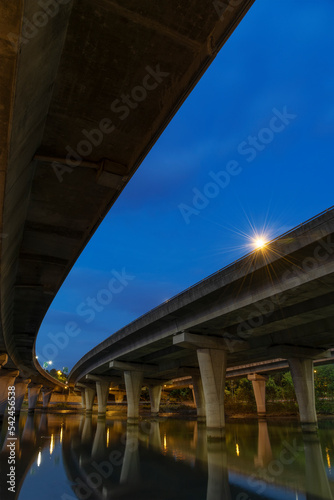 Underside of an elevated road across river at dusk