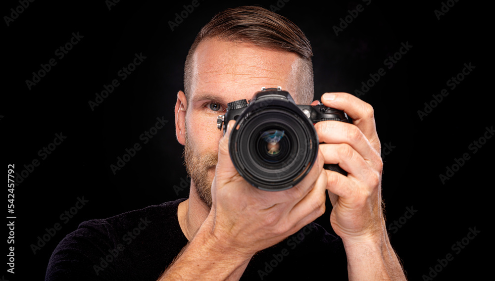 A man with a beard takes pictures with a camera on a dark background. A man with a beard takes pictures with a camera on a dark background.