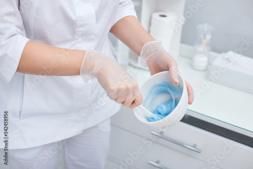 bowl with blue alginate mask in hands of beautician. © producer