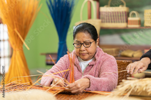 Senior Hispanic woman crafting grass basket