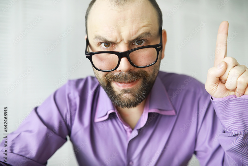 A cross-eyed bearded man is looking into the frame. Eye disease. The concept of an inexperienced specialist. Spy neighbor. A cross-eyed bearded man is looking into the frame. Eye disease. The concept of an inexperienced specialist. Spy neighbor.