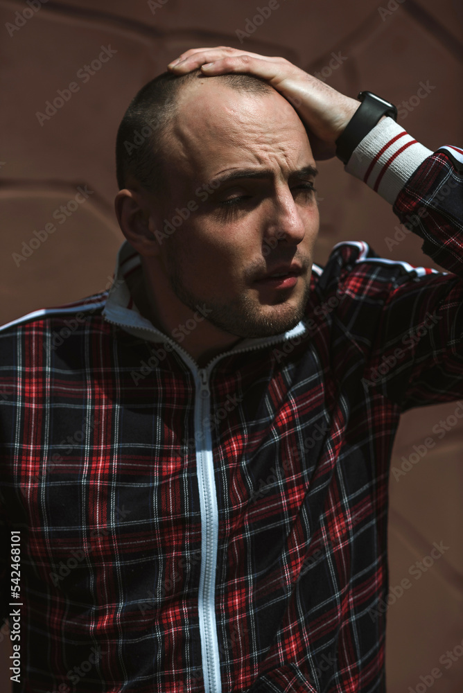 male portrait on the street in sunlight; dressed in a red and black suit