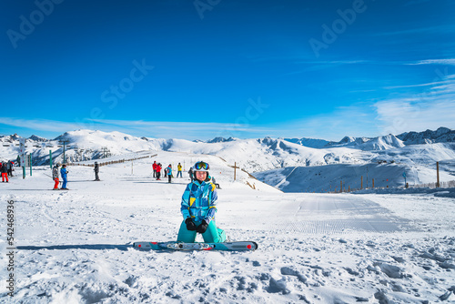 Portrait of a woman skier looking at camera with people skiing on the back, Pyrenees Mountains. Winter ski holidays in El Tarter, Grandvalira Andorra