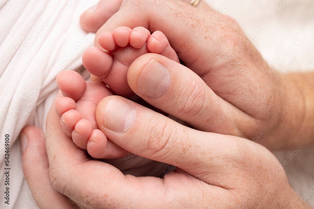 Mother and father are doing massage on her baby foot. Closeup baby feet in mother hands. Prevention of flat feet, development, muscle tone, dysplasia. Family, love, care, and health concepts. Mother and father are doing massage on her baby foot. Closeup baby feet in mother hands. Prevention of flat feet, development, muscle tone, dysplasia. Family, love, care, and health concepts.