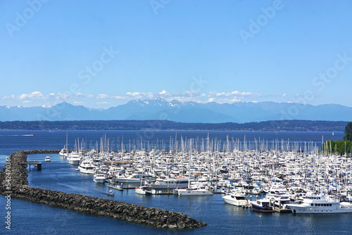 Seattle, Washington: Marina filled with sailboats on the deep blue waters of Elliott Bay, with snow-capped mountains in the distance.