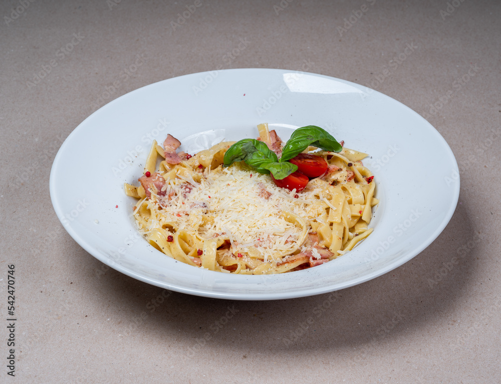 Close-up of Carbonara pasta with cheese and bacon in a white plate. Italian cuisine. Tasty food.