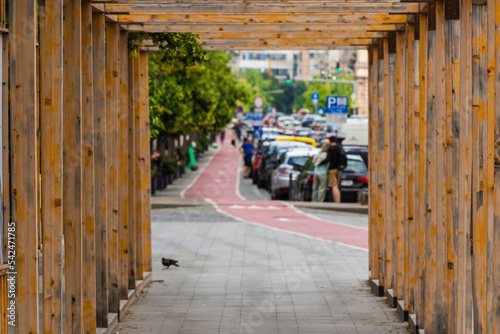 View through a wooden tunnel scaffolding for pedestrian protection with blurred town traffic in the distance © madrolly
