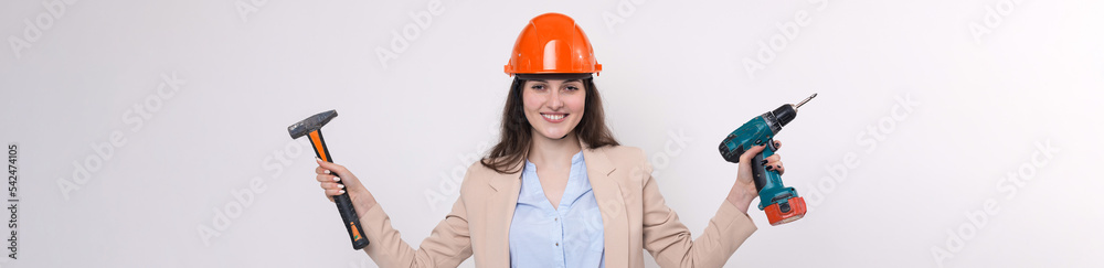 Girl engineer in an orange construction helmet with a screwdriver and a hammer on a white background. Girl engineer in an orange construction helmet with a screwdriver and a hammer on a white background.