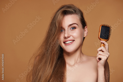 Beautiful smiling brunette woman showing wooden brush