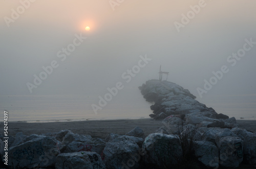 Un frangiflutti della spiaggia del Lido di Venezia con il sole che sorge in una nebbiosa giornata autunnale photo