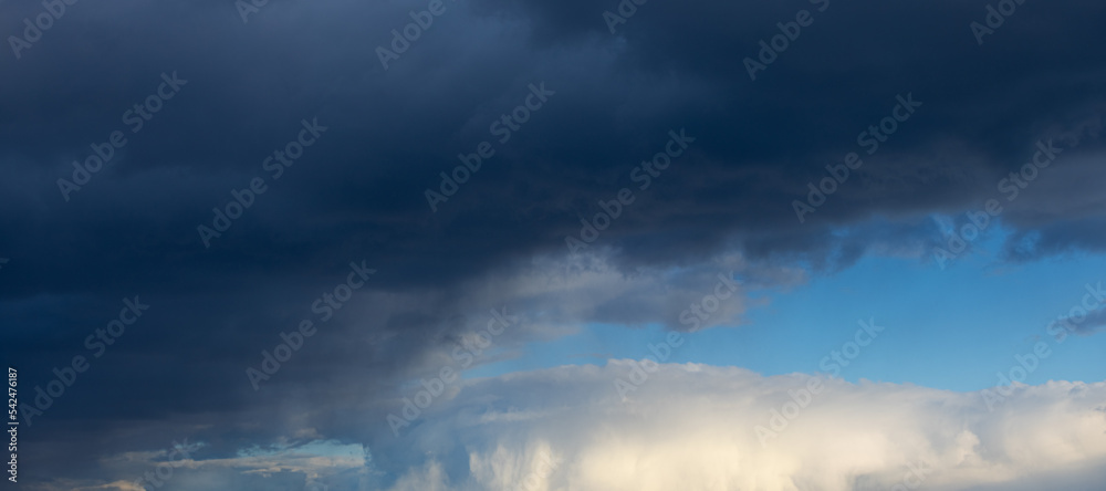 Panorama cloudy stormy sky. Dramatic background with grey and white cumulus fluffy clouds and bright blue sky Panorama cloudy stormy sky. Dramatic background with grey and white cumulus fluffy clouds and bright blue sky