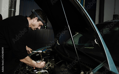 Repairman fixing engine of car in workshop photo