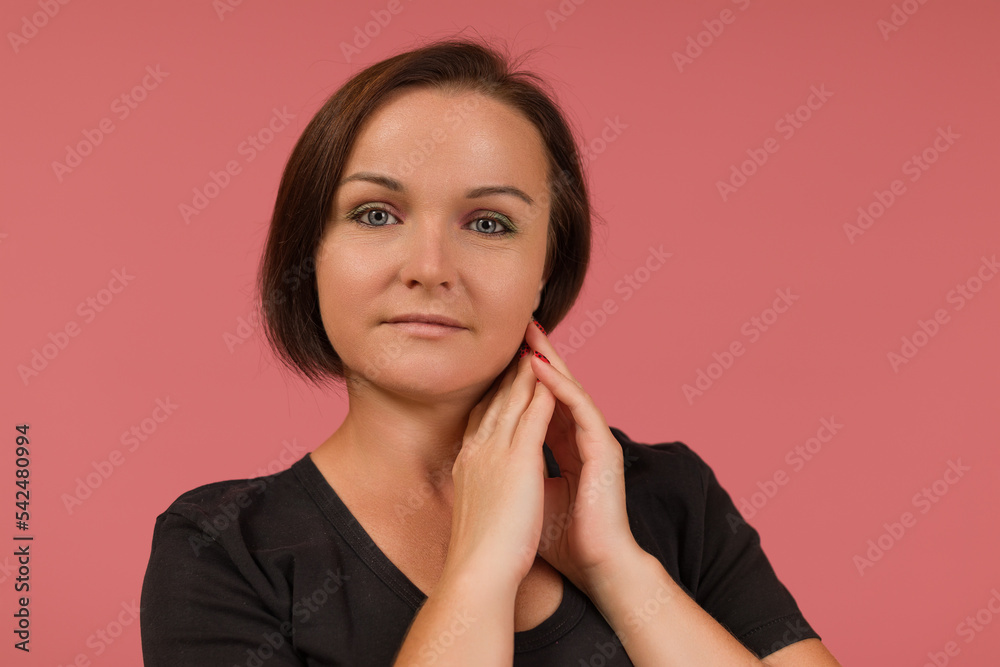 an adult woman with black hair with palms near her cheek looks at the camera. close-up an adult woman with black hair with palms near her cheek looks at the camera. close-up