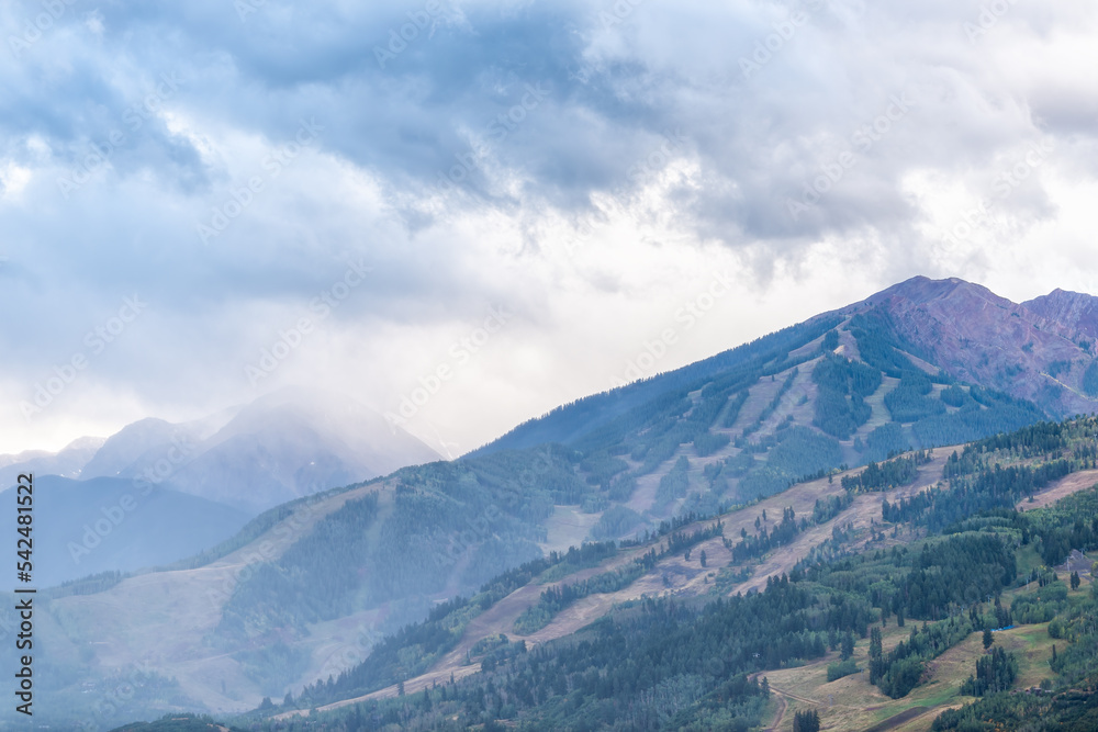 Dark cloudy sky in Aspen, Colorado with rocky mountains peak and mountain ridge in autumn with storm clouds and rain from high angle view